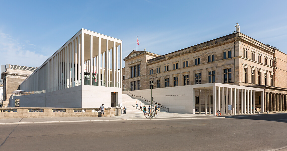 Blick auf ein sehr modernes Gebäude und die James Simon Galerie vor einem historischen Gebäude