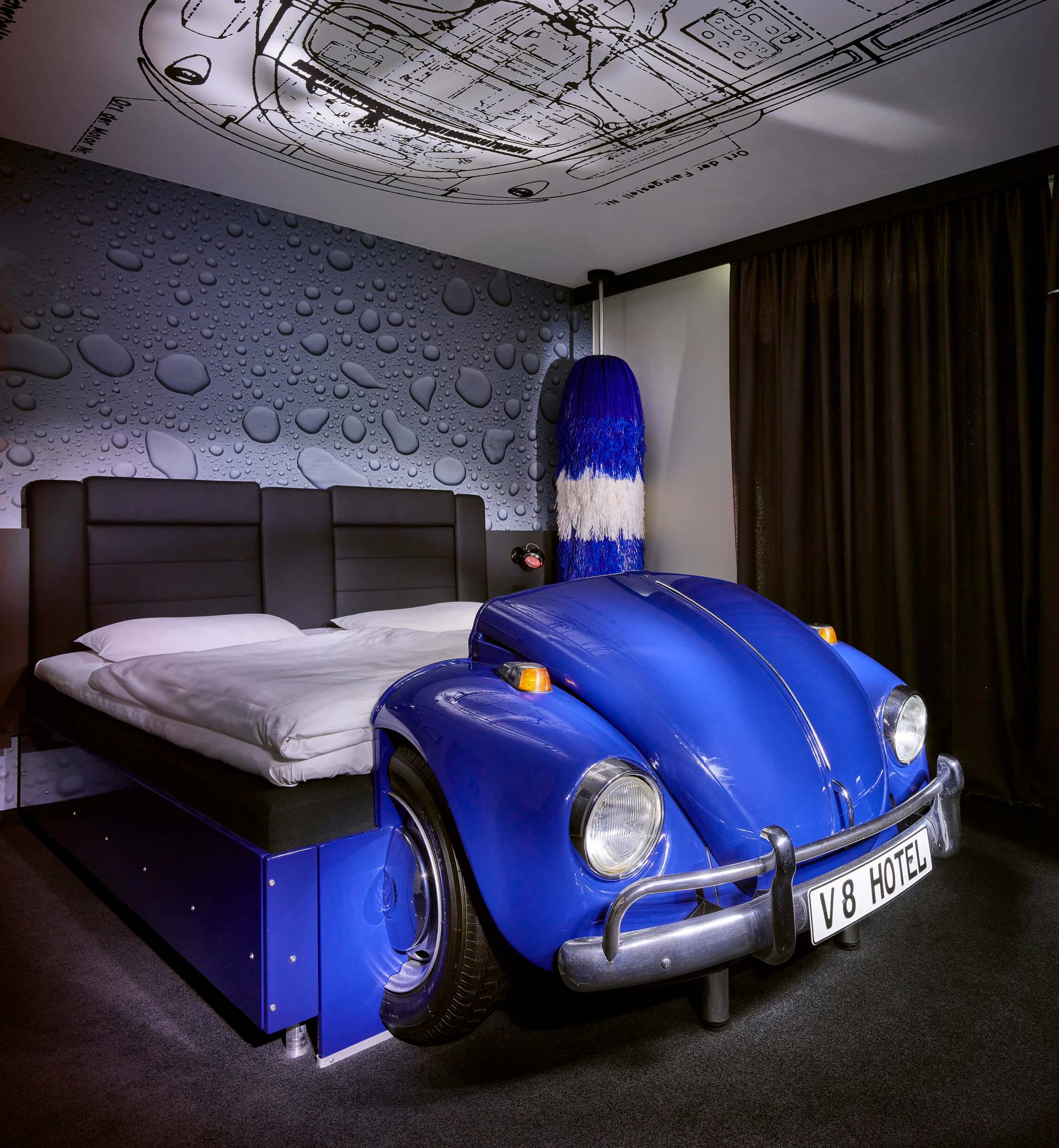 Ein Bett in Form eines Autos am Bettanfang im V8 Hotelzimmer in Koeln